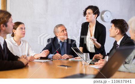 Focused colleagues of different ages discussing ideas and watching presentation while Latin female turning on presentation in meeting room 110637841