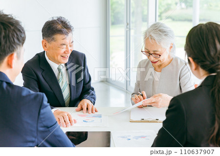 資料を見ながらカウンセリングを受ける高齢者夫婦（資産運用・商談・遺言書） 110637907