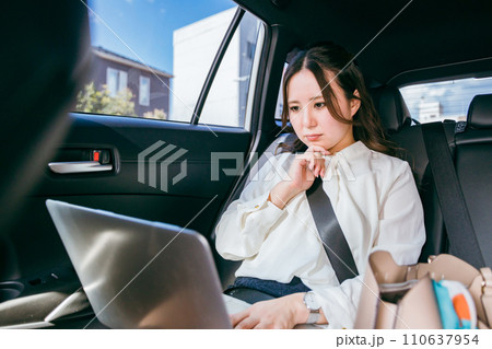 自動車の後部座席でノートパソコンで仕事をするビジネスウーマン（考える・困る・Web会議） 110637954