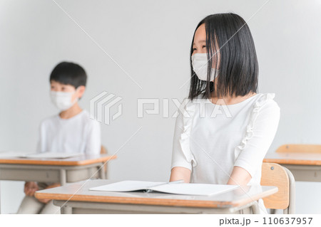 学校の教室でマスクをつけながら授業を受ける小学生 110637957