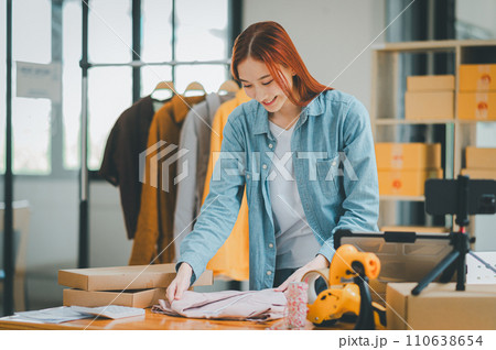 Online small business owners are packing their ordered products that customers order online into a box .concept of online shopping. Online small business owners are packing their ordered products that customers order online into a box .concept of online shopping. 110638654
