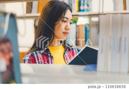 Students are reading and looking for books to study, make reports, find useful information on the bookshelves in the library. Concept of reading, learning and intelligence. Students are reading and looking for books to study, make reports, find useful information on the bookshelves in the library. Concept of reading, learning and intelligence. 110638656