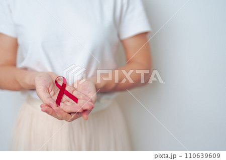 woman with Burgundy Red Ribbon for March multiple myeloma Cancer and December World Aids Day Awareness month. Healthcare and world cancer day concept 110639609