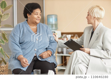 Portrait of distressed Black senior woman talking to caring female psychologist in therapy session 110640280