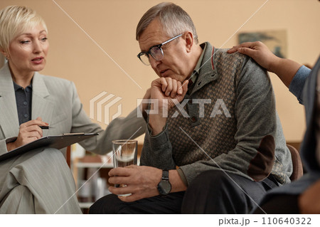 Side view portrait of senior man sharing mental health trouble with people comforting him during group therapy session Side view portrait of senior man sharing mental health trouble with people comforting him during group therapy session 110640322