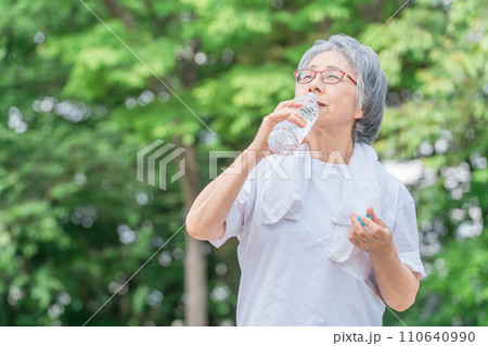公園で水を飲みながら運動・ウォーキング・歩く高齢者女性 公園で水を飲みながら運動・ウォーキング・歩く高齢者女性 110640990