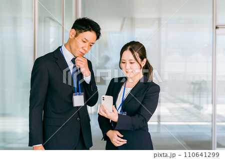 スマホを見ながら考え事をするビジネスマンとビジネスウーマン（ストレス・悩む・困る・問題） 110641299