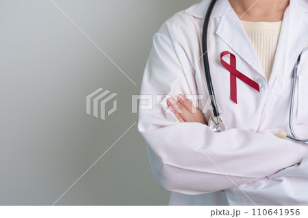 Doctor with Burgundy Red Ribbon for March multiple myeloma Cancer and December World Aids Day Awareness month. Healthcare and world cancer day concept Doctor with Burgundy Red Ribbon for March multiple myeloma Cancer and December World Aids Day Awareness month. Healthcare and world cancer day concept 110641956