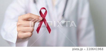 Doctor with Burgundy Red Ribbon for March multiple myeloma Cancer and December World Aids Day Awareness month. Healthcare and world cancer day concept Doctor with Burgundy Red Ribbon for March multiple myeloma Cancer and December World Aids Day Awareness month. Healthcare and world cancer day concept 110641968