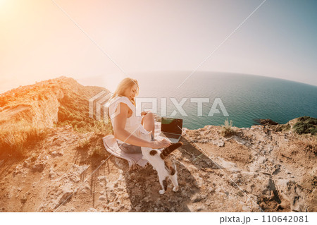 Woman sea laptop. Business woman petting cat and working on laptop by the sea. Close up on hands of pretty lady typing on computer outdoors summer day. Freelance, digital nomad and holidays concept. Woman sea laptop. Business woman petting cat and working on laptop by the sea. Close up on hands of pretty lady typing on computer outdoors summer day. Freelance, digital nomad and holidays concept. 110642081