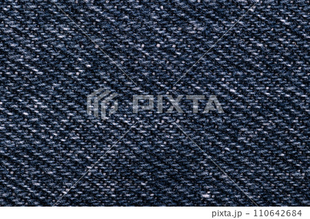 Denim surface, blue jeans fabric, front side, from above. Sturdy cotton warp-faced fabric. Type of textile weave with pattern of diagonal parallel ribs. Indigo dyed warp thread, and white weft thread. Denim surface, blue jeans fabric, front side, from above. Sturdy cotton warp-faced fabric. Type of textile weave with pattern of diagonal parallel ribs. Indigo dyed warp thread, and white weft thread. 110642684