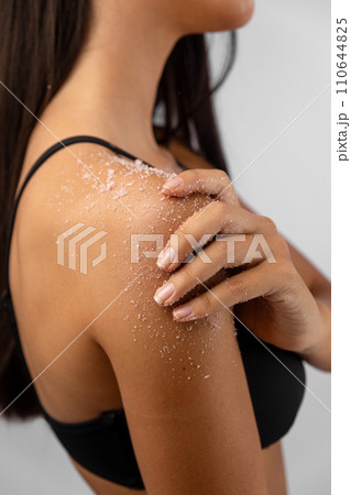 Young woman applying body scrub on her shoulder 110644825