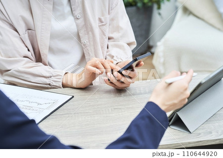 スマートフォンを手に説明を聞く女性の手元 スマートフォンを手に説明を聞く女性の手元 110644920