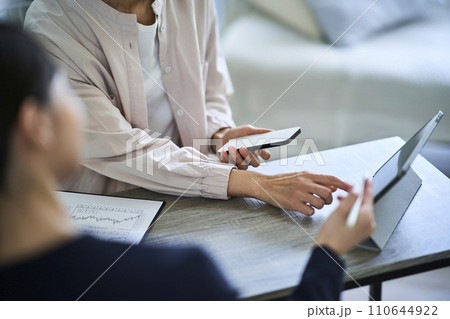スマートフォンを手に説明を聞く女性の手元 110644922