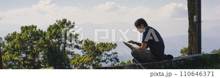 landscape and travel concept with solo freelancer man sit on wooden and use tablet work from outdoor with layer of mountain background landscape and travel concept with solo freelancer man sit on wooden and use tablet work from outdoor with layer of mountain background 110646371
