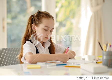 Creative schoolgirl drawing in textbook at school desk 110646798