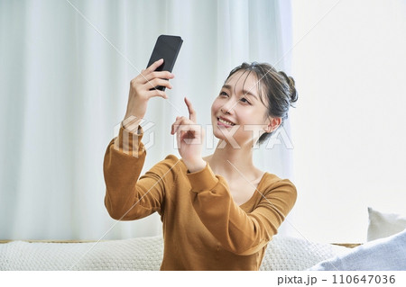 ルームウェアを着て、スマートフォンを操作する若い女性 110647036