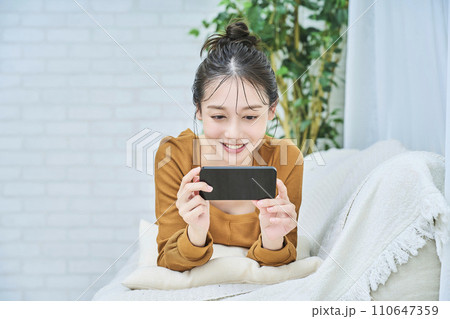 ルームウェアを着てスマートフォンの画面を見る若い女性 ルームウェアを着てスマートフォンの画面を見る若い女性 110647359