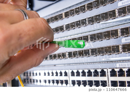 hand of administrator plugging in fiber optic cable into empty switchboard 110647666