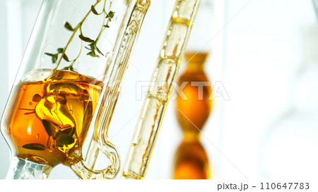 Getting natural oil from natural substances and flowers. Yellow oil flows in a spiral. 110647783