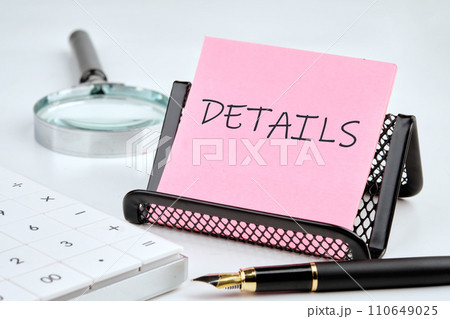 DETAILS word on the sticker on the stand on a white background next to a fountain pen, calculator and magnifying glass on a white background 110649025