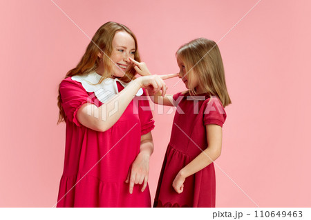 Playful parenting. Beautiful happy mother playing with her little Daubert against pink studio background. Mother's Day, International Happiness Day Playful parenting. Beautiful happy mother playing with her little Daubert against pink studio background. Mother's Day, International Happiness Day 110649463