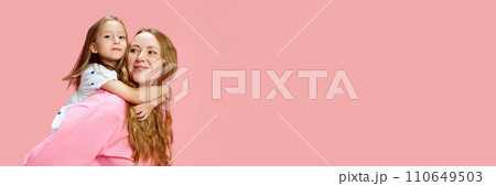 Portrait of beautiful young happy woman, mother with her little daughter against pink studio background. Mother's Day, International Happiness Day 110649503