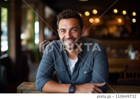 Portrait of handsome man smiling at camera in a pub or restaurant. 110649732