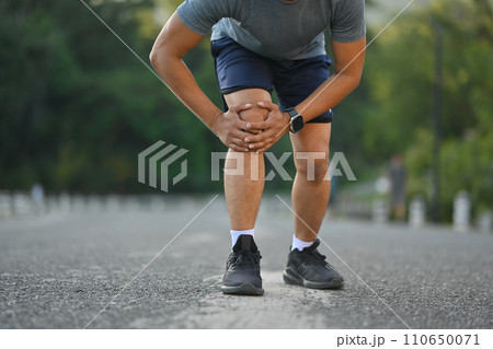Male athlete suffering ligament injury during running workout, training. Sport and health care concept Male athlete suffering ligament injury during running workout, training. Sport and health care concept 110650071
