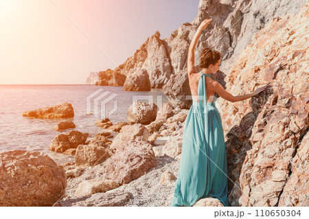 Side view a Young beautiful sensual woman with black hair in a long mint dress posing on a beach with calm sea bokeh lights on sunny day. Girl on the nature on blue sky background. Fashion photo Side view a Young beautiful sensual woman with black hair in a long mint dress posing on a beach with calm sea bokeh lights on sunny day. Girl on the nature on blue sky background. Fashion photo 110650304