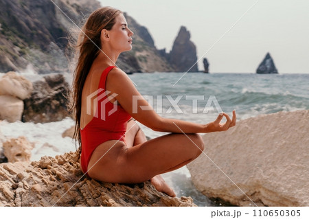 Woman sea yoga. Happy woman meditating in yoga pose on the beach, ocean and rock mountains. Motivation and inspirational fit and exercising. Healthy lifestyle outdoors in nature, fitness concept. 110650305