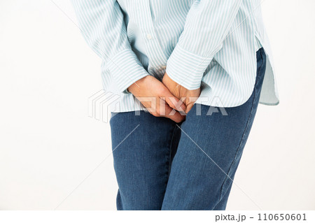 股間を押さえるミドル女性 110650601