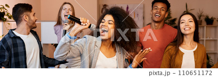 Singing means happiness. Pretty mixed race girl looking enthusiastic while holding microphone and singing at karaoke party with best friends. Happy multicultural people spending time together Singing means happiness. Pretty mixed race girl looking enthusiastic while holding microphone and singing at karaoke party with best friends. Happy multicultural people spending time together 110651172