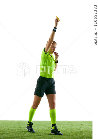 Serious woman, soccer referee gesturing, raising hand, stopping game and showing yellow card as warning against white studio background Serious woman, soccer referee gesturing, raising hand, stopping game and showing yellow card as warning against white studio background 110652383