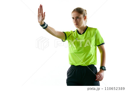Young serious woman, soccer referee gesturing, raising hand forward meaning penalty kick against white studio background Young serious woman, soccer referee gesturing, raising hand forward meaning penalty kick against white studio background 110652389