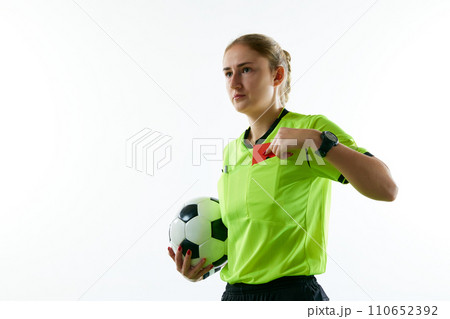 Young woman, female soccer referee holding ball, stopping game and showing red card against white studio background 110652392