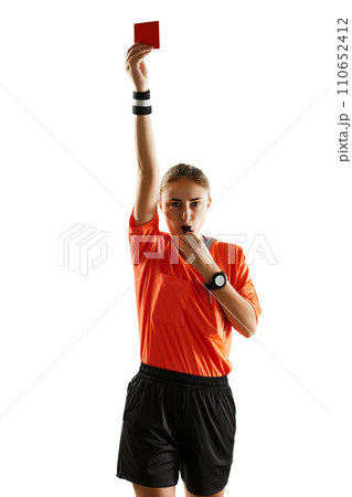 Young concentrated woman, soccer referee blowing a whistle and showing red card as dismissal symbol against white studio background 110652412