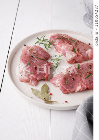 a piece of fresh raw pork meat with spices on a white wooden table. Meat with spices a piece of fresh raw pork meat with spices on a white wooden table. Meat with spices 110654287