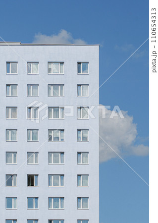 the pale blue facade of an apartment building against a clear sky 110654313