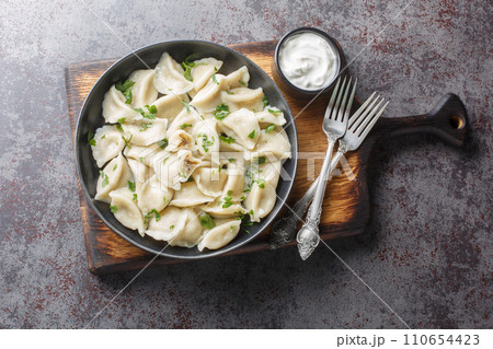 Traditional Polish Christmas Eve mushroom dumplings uszka served with sour cream closeup on the plate. Horizontal top view 110654423
