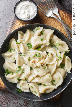 Traditional Polish ravioli dumplings or uszka served with sour cream closeup on the plate on the table. Vertical top view 110654433