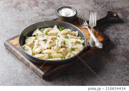 Traditional Polish Christmas Eve mushroom dumplings uszka served with sour cream closeup on the plate. Horizontal 110654434
