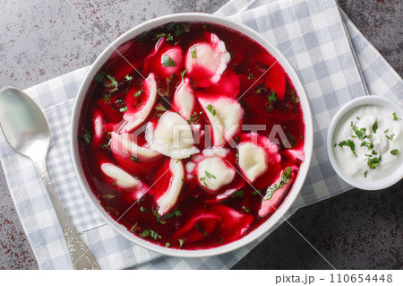 Old Polish beetroot borscht with traditional uszka dumplings stuffed with cabbage and mushrooms close-up in a bowl. Horizontal top view Old Polish beetroot borscht with traditional uszka dumplings stuffed with cabbage and mushrooms close-up in a bowl. Horizontal top view 110654448