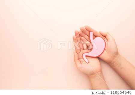 Human hands holding stomach organ made from paper on beige background. Concept of gastric cancer screening, stomach transplant, digestive tract problem and stomach disease treatment. Flat layout. 110654646