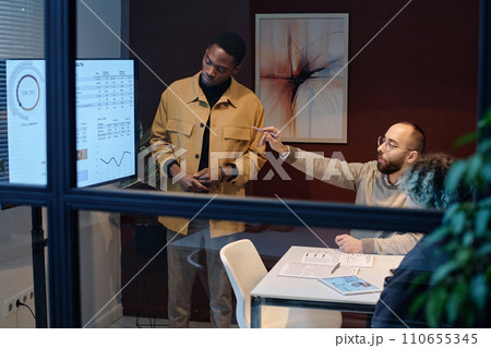 Colleagues discussing data presented on display in office conference room Colleagues discussing data presented on display in office conference room 110655345