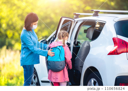 Mother putting daughter in car after classes during coronavirus epidemic Mother putting daughter in car after classes during coronavirus epidemic 110656824