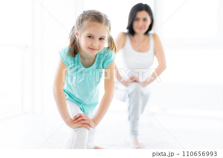 Cute little girl with trainer doing lunges in gym Cute little girl with trainer doing lunges in gym 110656993