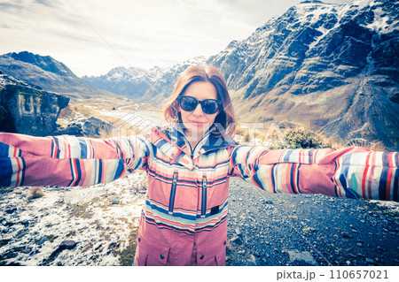 Happy smiling girl with black glasses taking selfie on the background of amazing rocky Andes 110657021