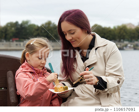 Young mother with a little daugter, the models eating dessert. Young mother with a little daugter, the models eating dessert. 110657091
