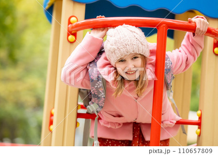 Pretty girl kid playing on playground at autumn day outdoors. Female child having fun at the street Pretty girl kid playing on playground at autumn day outdoors. Female child having fun at the street 110657809
